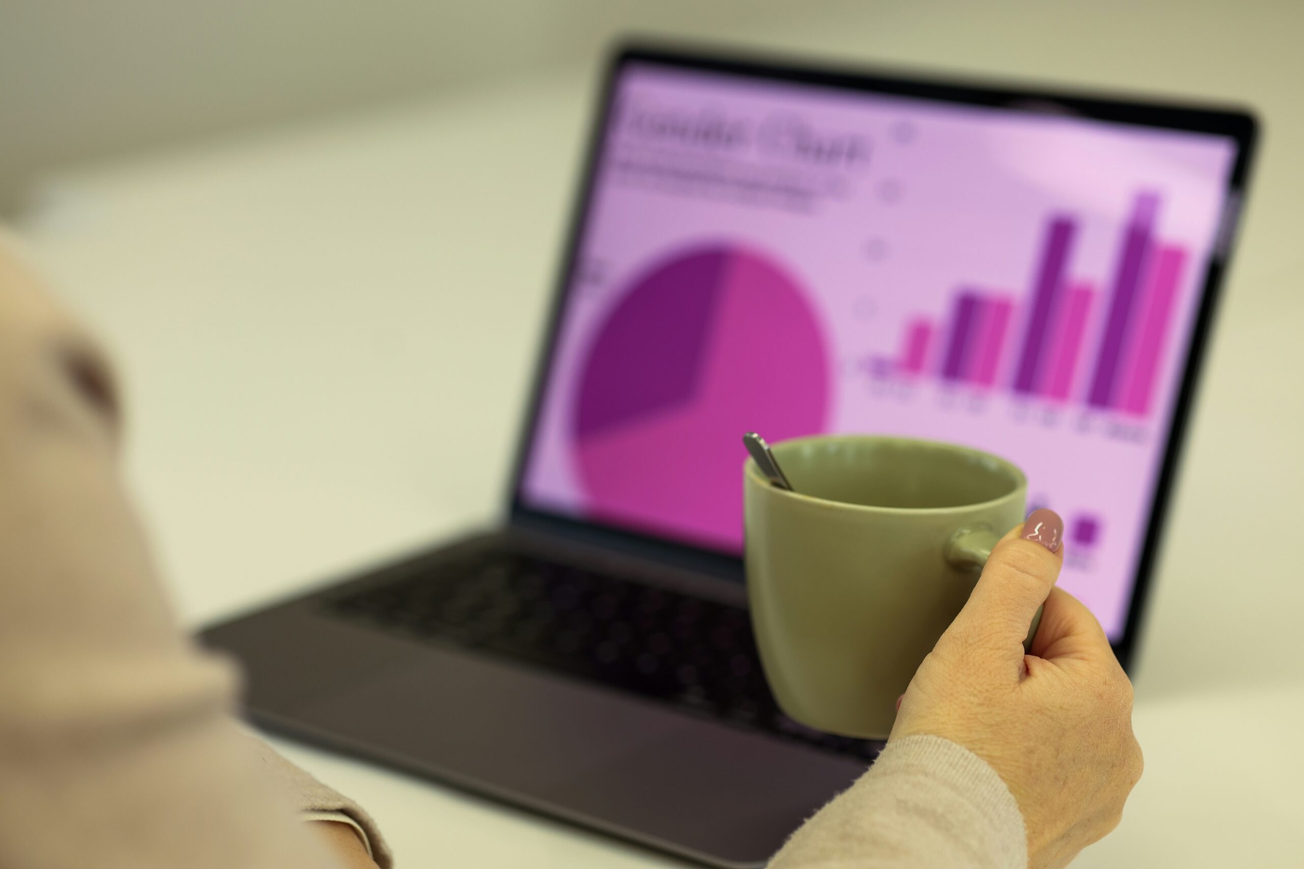 person holding mug while analysing data - purple pie charts and graphs